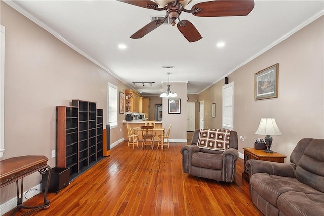 living room with ornamental molding, wood-type flooring, and ceiling fan with notable chandelier