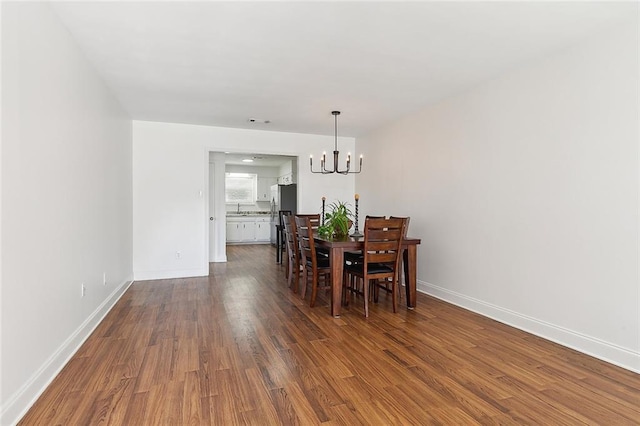 dining area featuring sink, dark hardwood / wood-style flooring, and a notable chandelier