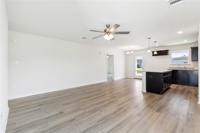 kitchen featuring ceiling fan with notable chandelier, sink, a center island, pendant lighting, and light hardwood / wood-style floors