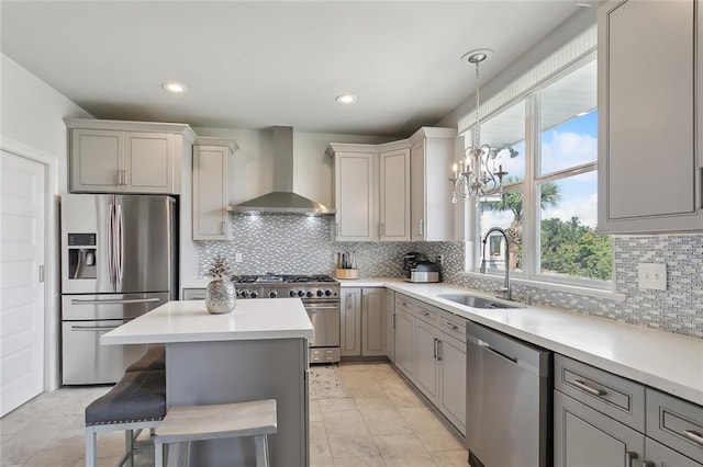 kitchen featuring sink, wall chimney exhaust hood, an inviting chandelier, gray cabinets, and appliances with stainless steel finishes