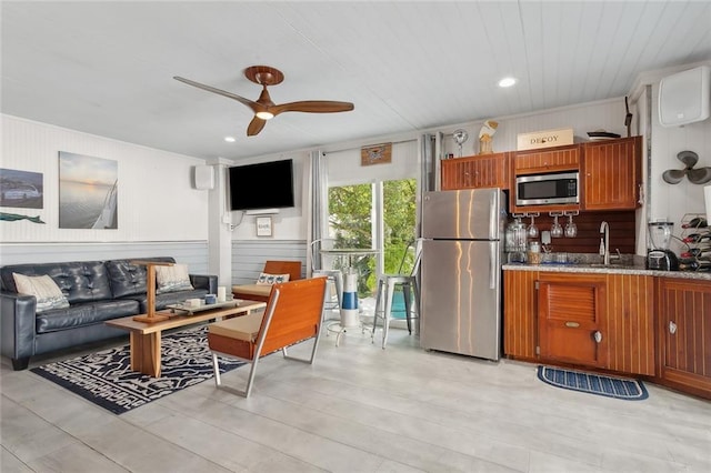 kitchen with ceiling fan, a wall mounted air conditioner, wooden walls, appliances with stainless steel finishes, and ornamental molding