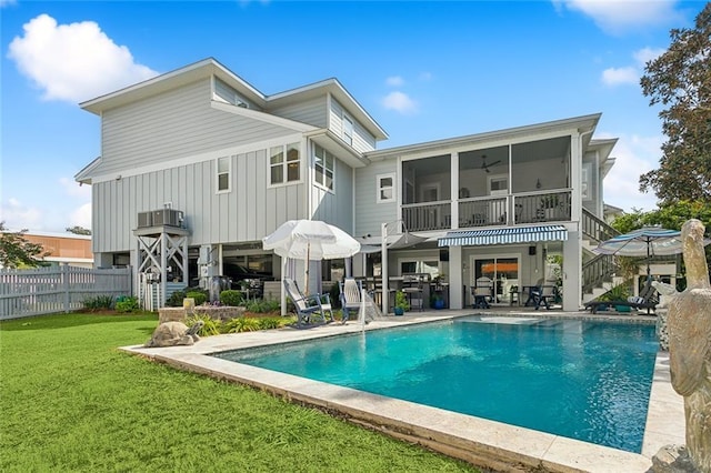 rear view of house featuring a sunroom, a fenced in pool, a yard, and a patio