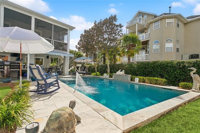 view of pool featuring a sunroom, pool water feature, a patio area, and ceiling fan