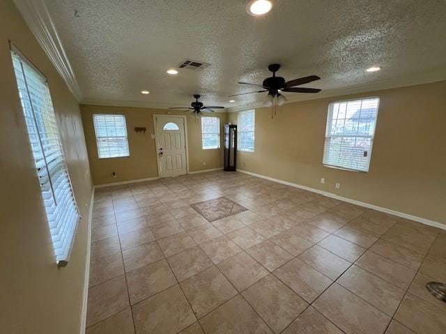 tiled entryway with ornamental molding, ceiling fan, a textured ceiling, and a wealth of natural light