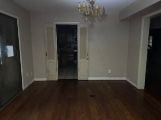 spare room with a chandelier and dark hardwood / wood-style floors