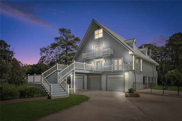 view of front of property featuring a balcony, driveway, stairs, an attached garage, and fence