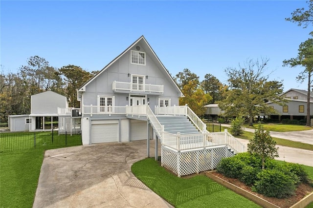 view of front of house featuring stairs, a balcony, a front yard, fence, and a garage