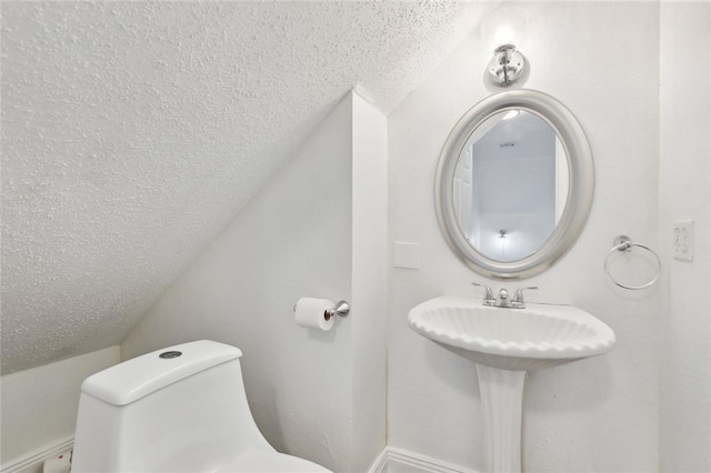 bathroom featuring toilet, a textured ceiling, and lofted ceiling