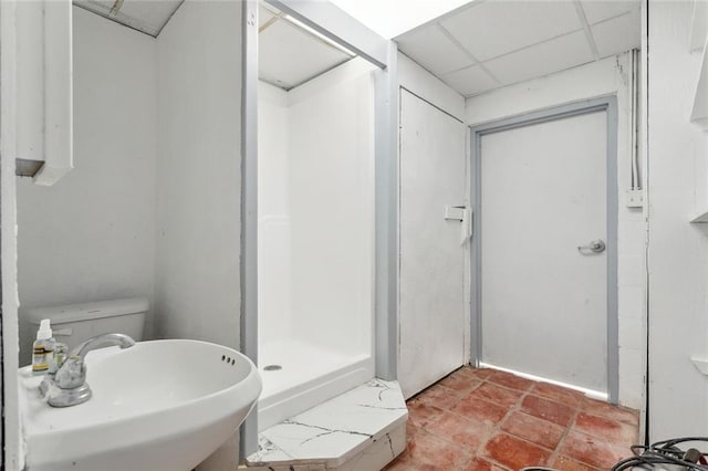 full bathroom with a stall shower, a drop ceiling, and a sink