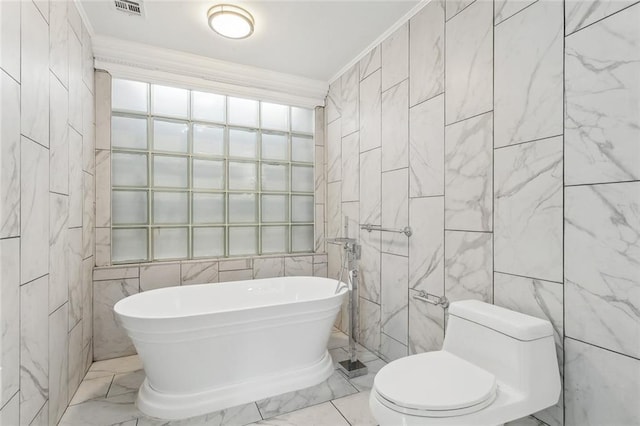 full bath featuring visible vents, toilet, ornamental molding, tile walls, and a freestanding tub