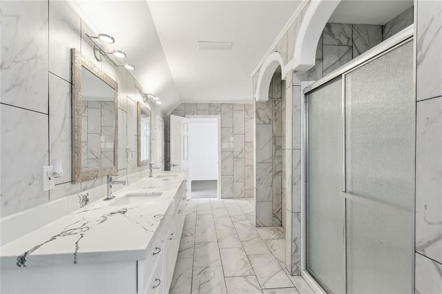 bathroom with tile walls, marble finish floor, lofted ceiling, and a sink