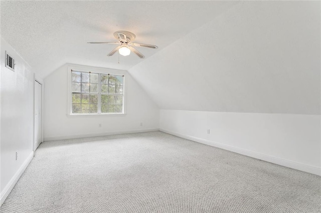 additional living space featuring vaulted ceiling, light carpet, ceiling fan, baseboards, and visible vents