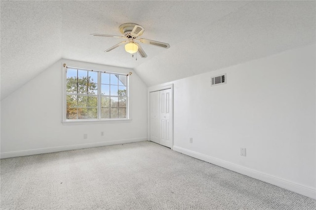 additional living space with vaulted ceiling, ceiling fan, a textured ceiling, and light colored carpet