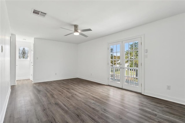 spare room featuring dark wood finished floors, baseboards, visible vents, and a ceiling fan