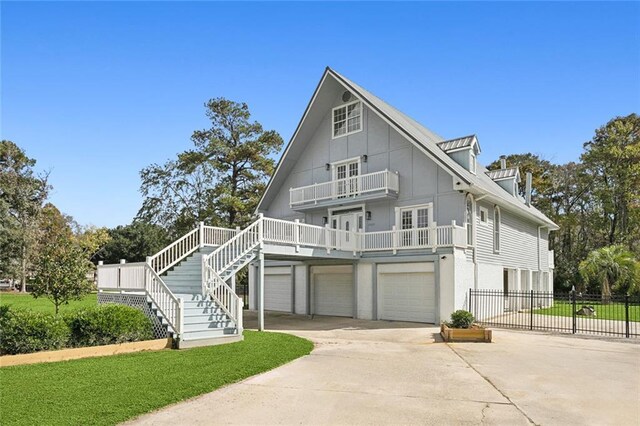 view of front facade with stairway, fence, a garage, driveway, and a balcony
