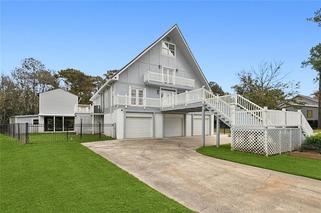 rear view of house featuring concrete driveway, an attached garage, fence, stairway, and a yard