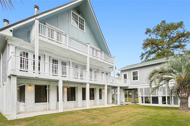 back of property featuring a patio area, a balcony, and a lawn