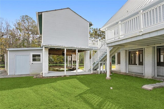 back of property featuring a lawn, a wooden deck, a patio, and stairway