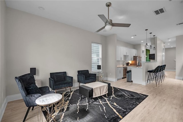 living room featuring sink, light hardwood / wood-style flooring, and ceiling fan