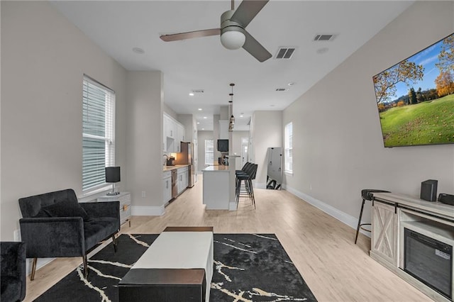 living room featuring light hardwood / wood-style floors and ceiling fan