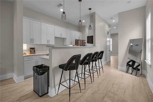 kitchen featuring stainless steel fridge, white cabinets, decorative light fixtures, and light hardwood / wood-style floors