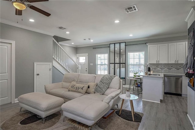 living room with light hardwood / wood-style flooring, ceiling fan, crown molding, and sink