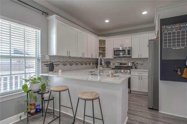 kitchen with kitchen peninsula, appliances with stainless steel finishes, white cabinetry, and sink