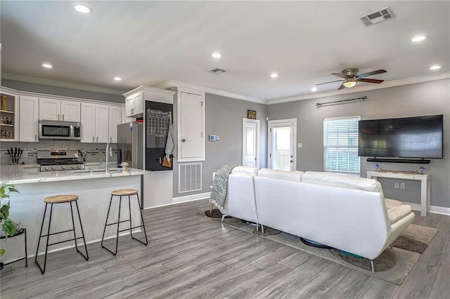 living room with ceiling fan, crown molding, and light wood-type flooring