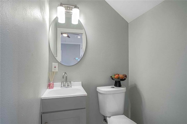 bathroom with vanity, toilet, and lofted ceiling