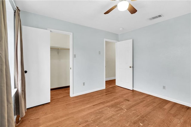 unfurnished bedroom with light hardwood / wood-style floors, a closet, a spacious closet, and ceiling fan