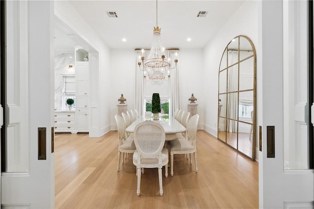 dining space with light hardwood / wood-style floors and a notable chandelier