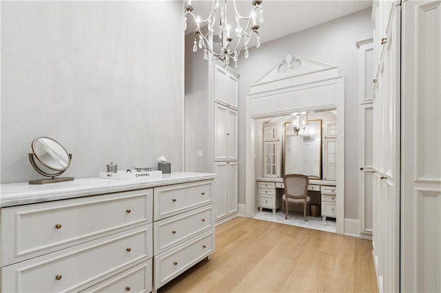 spacious closet with light hardwood / wood-style floors and built in desk