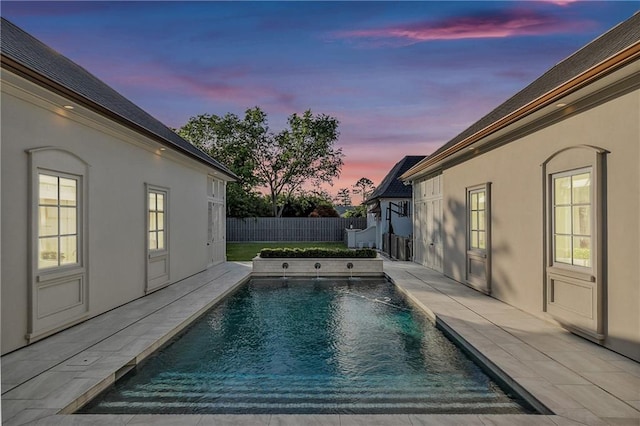 pool at dusk featuring a patio area