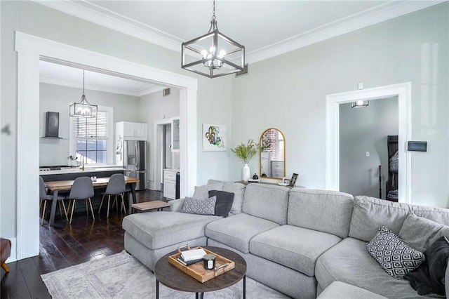 living room with dark wood-type flooring, crown molding, and a chandelier