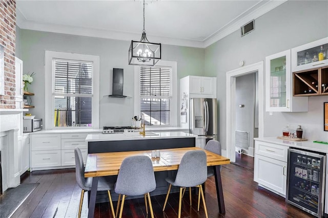 interior space with white cabinetry, stainless steel appliances, wall chimney exhaust hood, and beverage cooler