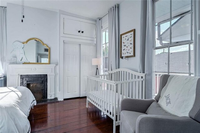 bedroom featuring a high end fireplace, a closet, multiple windows, and dark hardwood / wood-style floors