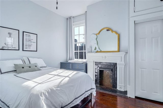 bedroom featuring dark hardwood / wood-style flooring and a fireplace