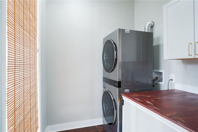 laundry area with cabinets, stacked washing maching and dryer, and dark hardwood / wood-style flooring