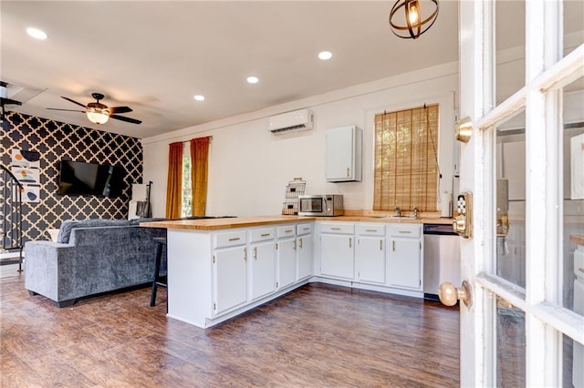 kitchen with appliances with stainless steel finishes, white cabinetry, ceiling fan, dark wood-type flooring, and a wall mounted AC