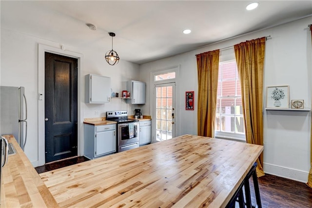 kitchen featuring appliances with stainless steel finishes, dark wood-type flooring, butcher block counters, and decorative light fixtures