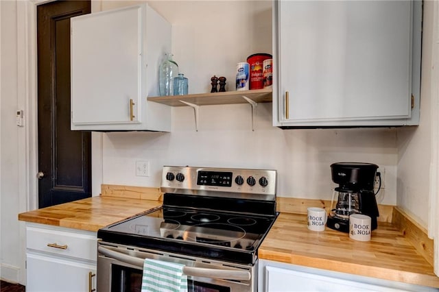 kitchen featuring butcher block counters, stainless steel range with electric cooktop, and white cabinetry