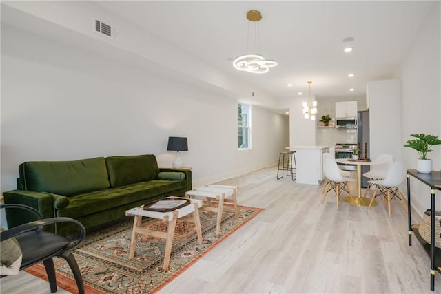 living room featuring light hardwood / wood-style floors and an inviting chandelier