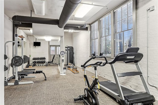 workout area with carpet floors and brick wall