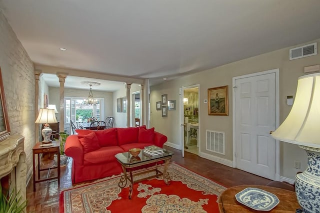 living room with dark wood-type flooring, decorative columns, and an inviting chandelier