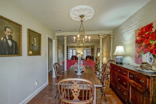 dining room with decorative columns and an inviting chandelier