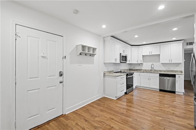 kitchen with white cabinets, light stone countertops, light hardwood / wood-style flooring, sink, and stainless steel appliances