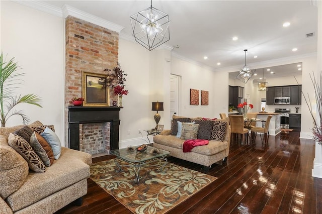 living room featuring a brick fireplace, dark hardwood / wood-style floors, an inviting chandelier, and ornamental molding