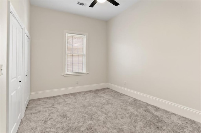 unfurnished bedroom featuring a closet, light colored carpet, and ceiling fan