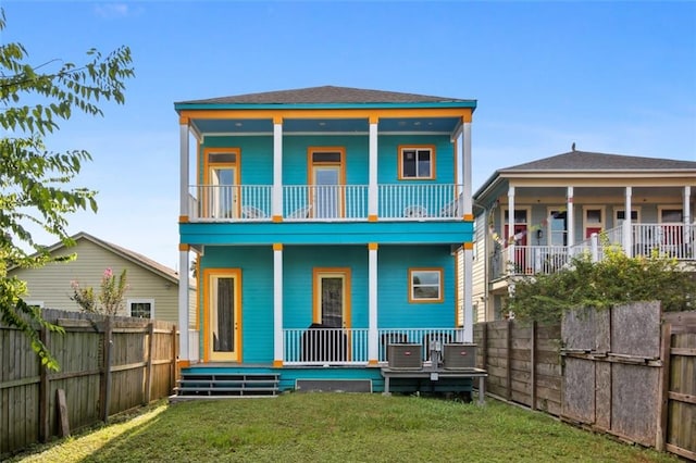 rear view of property with a porch, a lawn, and a balcony