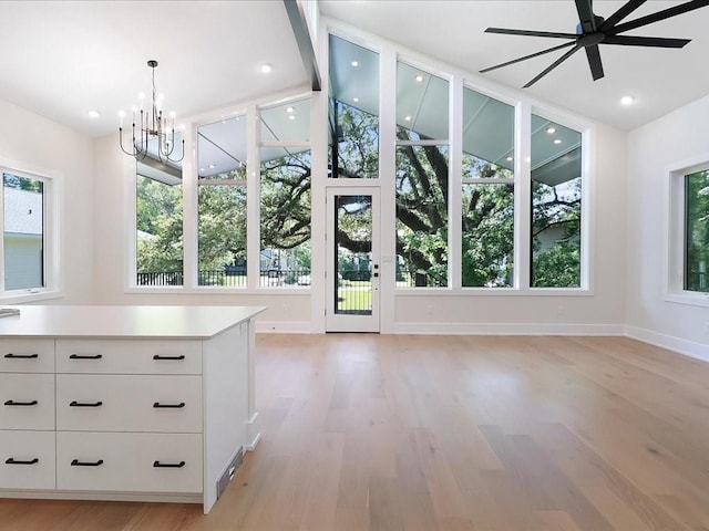 interior space with light hardwood / wood-style floors, ceiling fan with notable chandelier, and a wealth of natural light